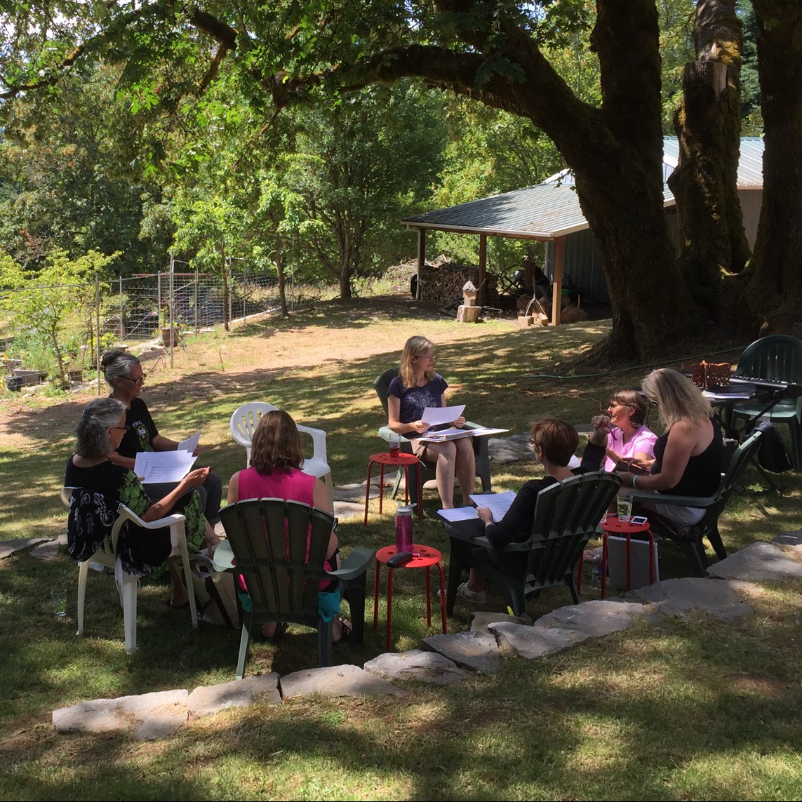 people sitting in a group under a giant maple tree