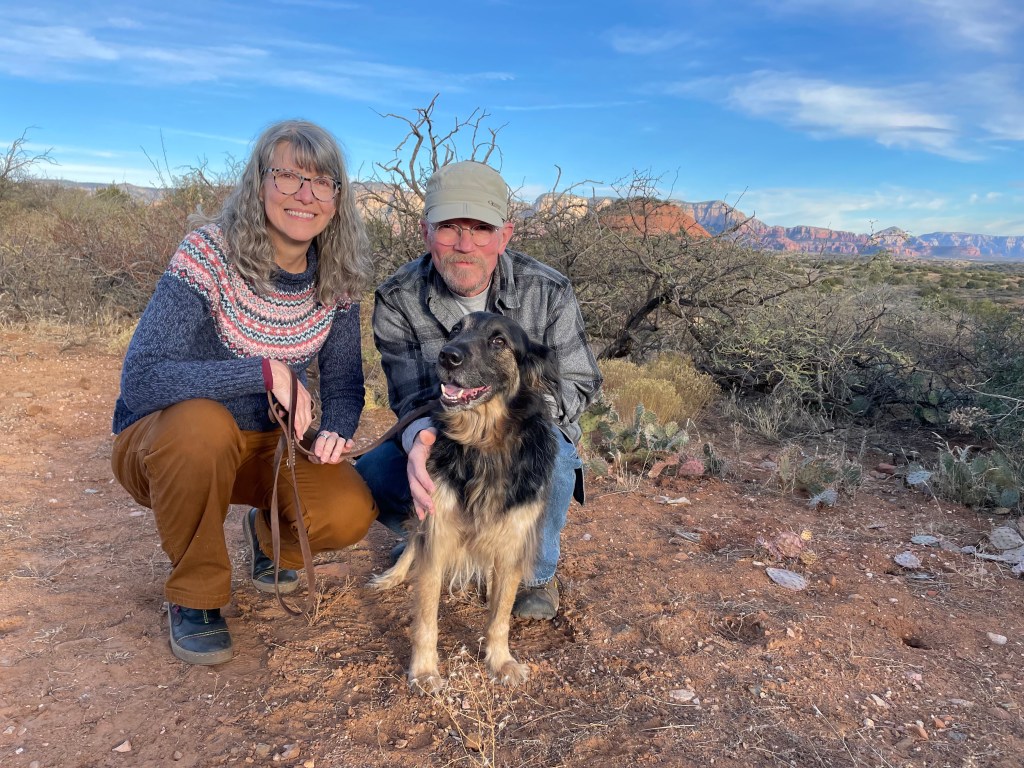 Jennifer, Jamie and Henry -- a smiling rescue dog -- in Sedona, Arizona, with the red rocks in the background.
